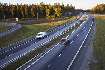 Väg 73 med ett par bilar med skog i bakgrunden