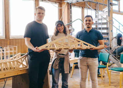 Albin Gordon Jonsson och två av medlemmarna i hans grupp visar upp en modell av det vinnande broförs