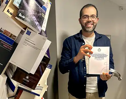 A man holding a thesis and a hammer